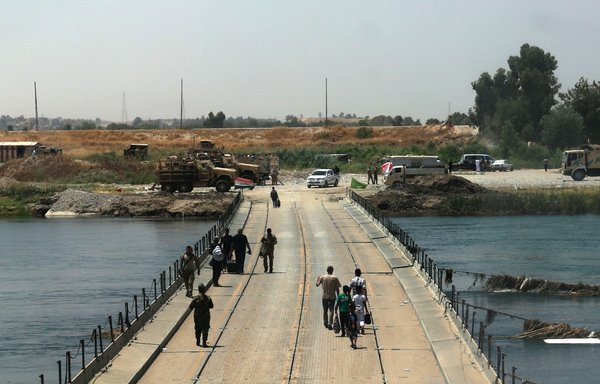 Iraqis cross a bridge connecting west and east Mosul on July 13, 2017, a few days after the government's announcement of the 'liberation' of the embattled city from ISIS. [Safin Hamed/AFP]