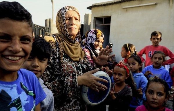 A Syrian woman drums on a tabla as she dances with children during the celebrations of the first wedding after the ouster of ISIS from the eastern city of al-Raqa, on October 27, 2017. [Delil Souleiman/AFP]