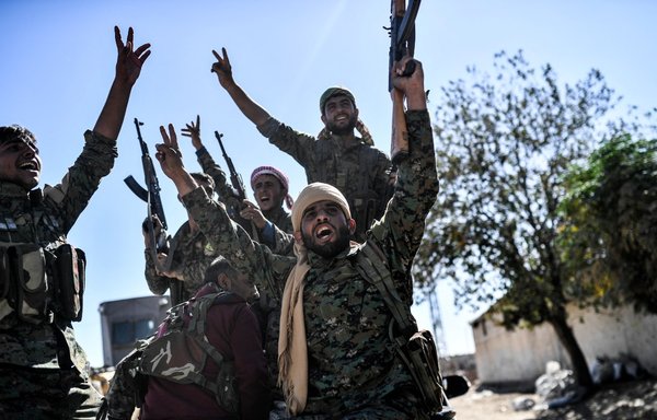 Members of the Syrian Democratic Forces (SDF), backed by US special forces, celebrate at the frontline in al-Raqa on October 16, 2017, after they retook the city from ISIS. [Bulent Kilic/AFP]