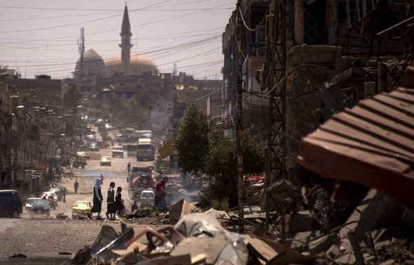 Iraqis walk on a damaged street in west Mosul on July 12, 2017, a few days after the government's announcement of the 'liberation' of the embattled city from ISIS. [Fadel Senna/AFP]